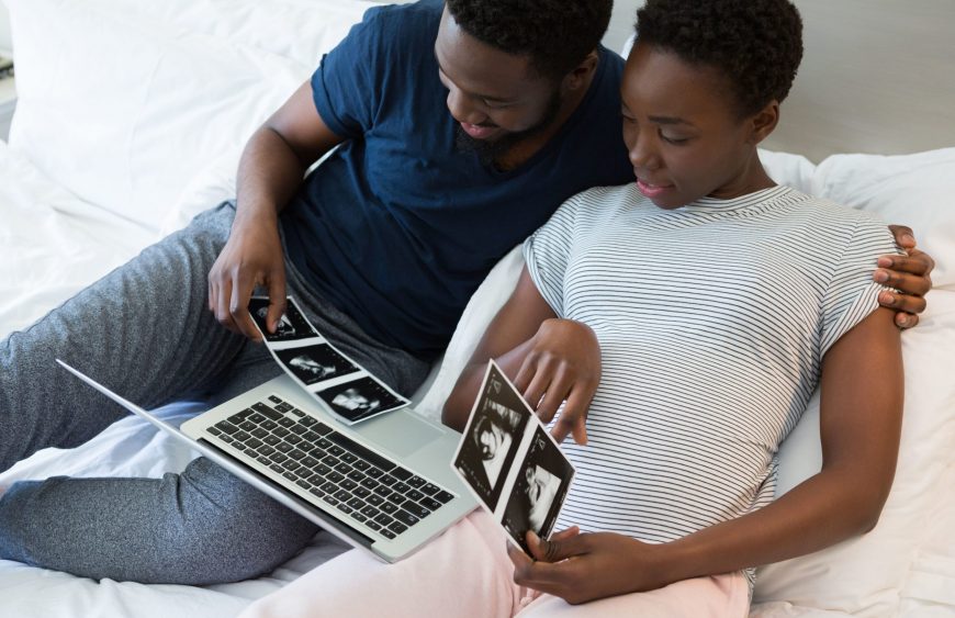 pikwizard-man-and-pregnant-woman-looking-at-sonography-in-bedroom-scaled-1